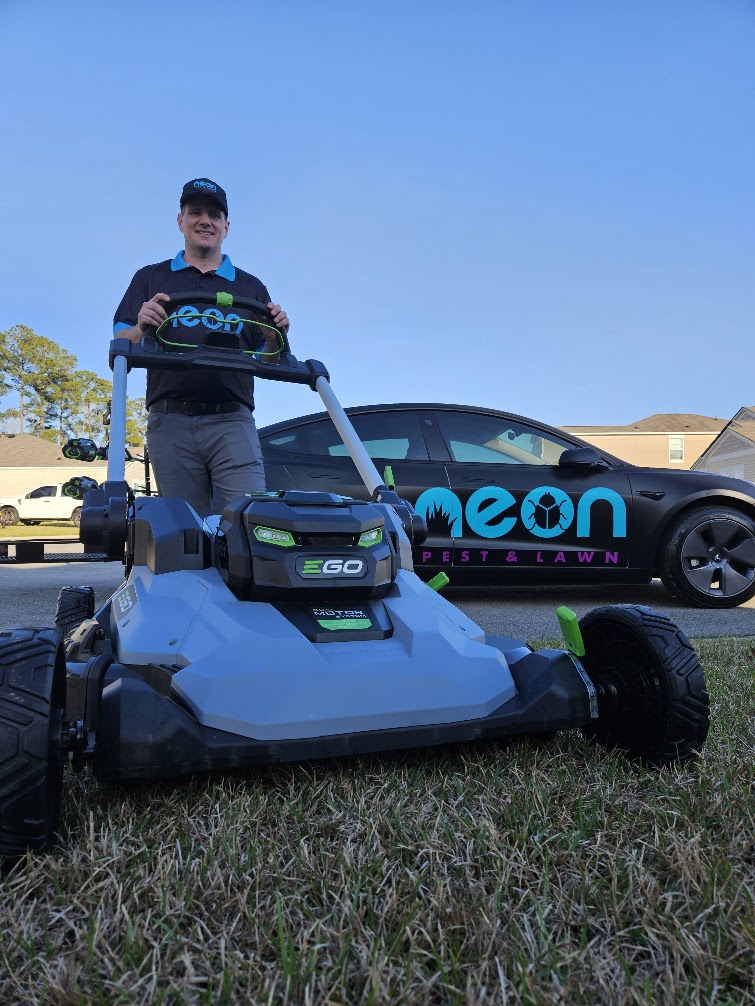 Neon crew mowing a large open farm-country lawn in Aynor