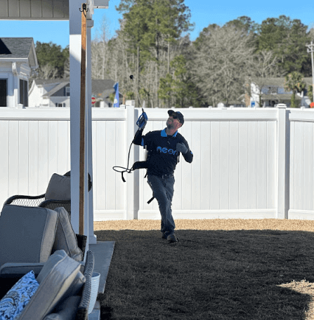 A Neon Pest and Lawn employee in black attire holds a hose, ready to provide pest control services in Loris, SC.