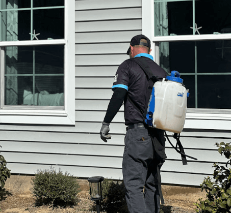 A Neon Pest and Lawn employee with a backpack sprayer