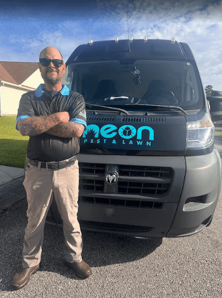 A man in uniform stands by a van labeled Neon, representing Neon Pest and Lawn in Horry County.