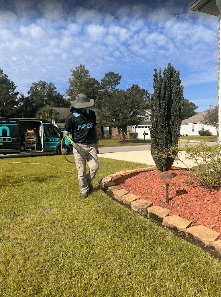 An employee of Neon Pest and Lawn a man in a hat and black shirt
