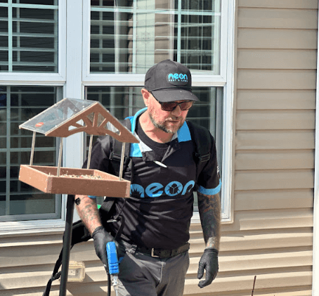 An employee of Neon Pest and Lawn showcases a bird feeder on his shoulder