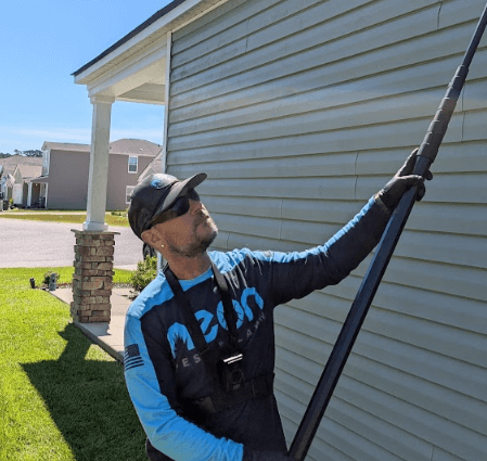 An employee of Neon Pest and Lawn uses a pole to exterminate bees at a client's house during a bee control service.