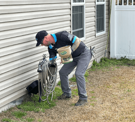 A Neon Pest and Lawn employee repairs a hose on a house, ensuring optimal residential lawn care maintenance.