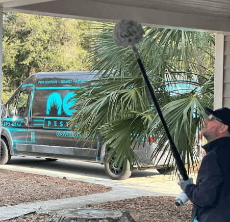 A Neon Pest and Lawn employee uses a broom to clean and exterminate bees at a client's house.
