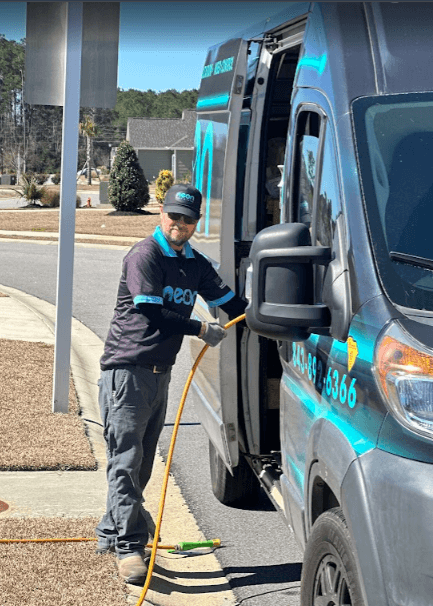 A Neon Pest and Lawn employee uses a hose to care commercial properties