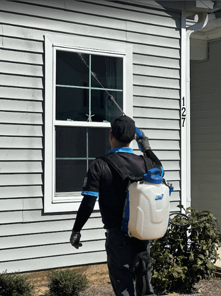 employee uses a sprayer to control pest for a house by neon pest control service
