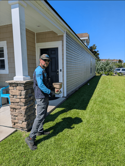 A man strolls across a lush lawn in front of a house, highlighting the benefits of a lawn fertilizer service.